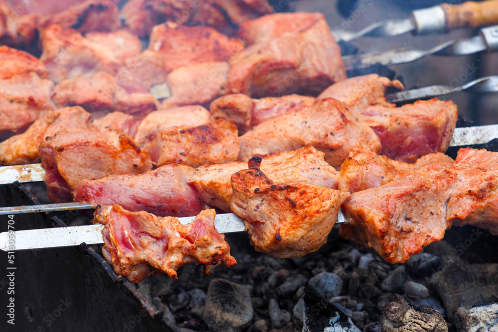 Close-up of meat on barbecue grill with smoke. Delicious grilled meat in BBQ. Barbecue, kebabs on the grill Close-up of meat on barbecue grill with smoke. Delicious grilled meat in BBQ. Barbecue, kebabs on the grill