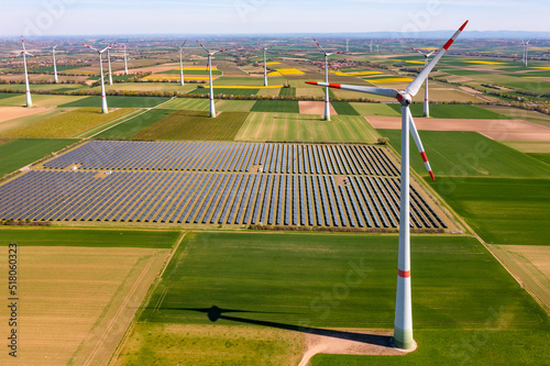 Solar panels of a solar park with wind turbines for the production of renewable energies for the German Energiewende seen from the air