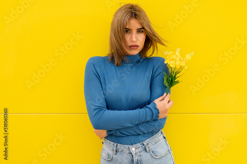 Young woman in casual clothes posing with a bouquet of yellow flowers on a color Fototapet