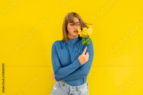 Canvastavla Young woman in casual clothes posing with a bouquet of yellow flowers on a color