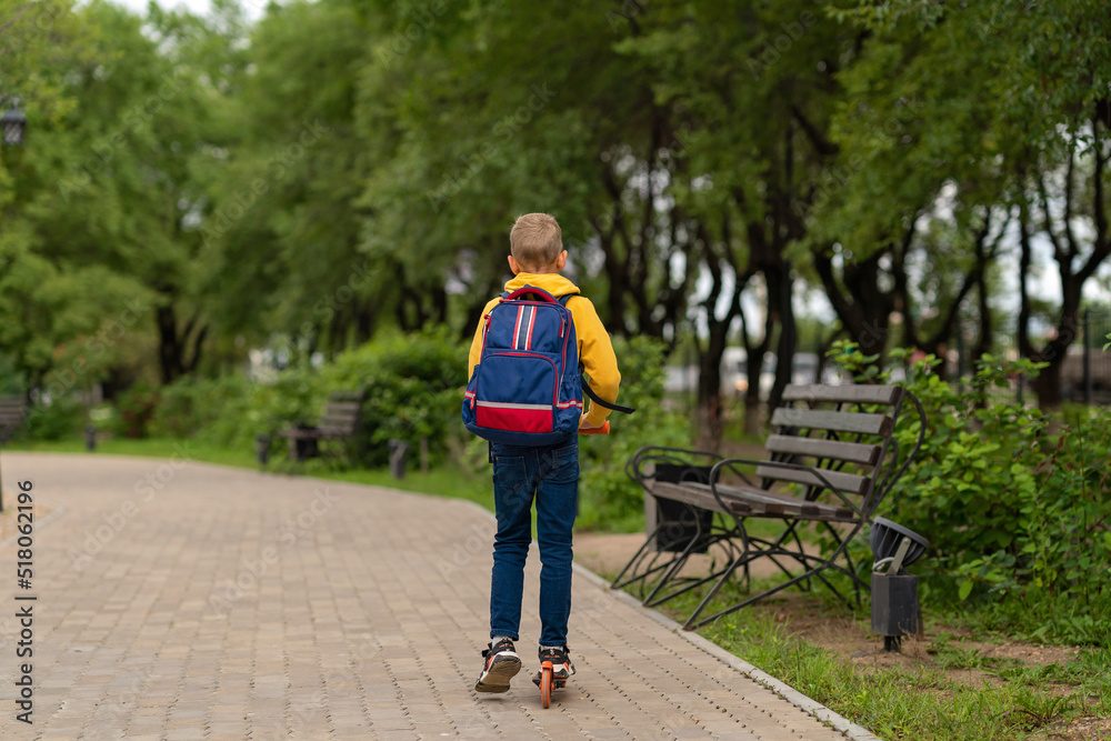 Fototapeta premium boy in a yellow sweatshirt with a backpack on his back going to school. back to school concept 