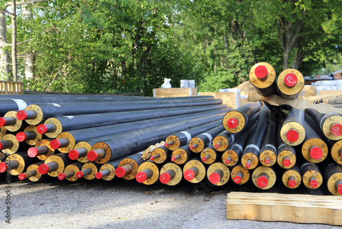 Different dimensions of heating pipes laying near a construction site. Sustainable energy concept. photo