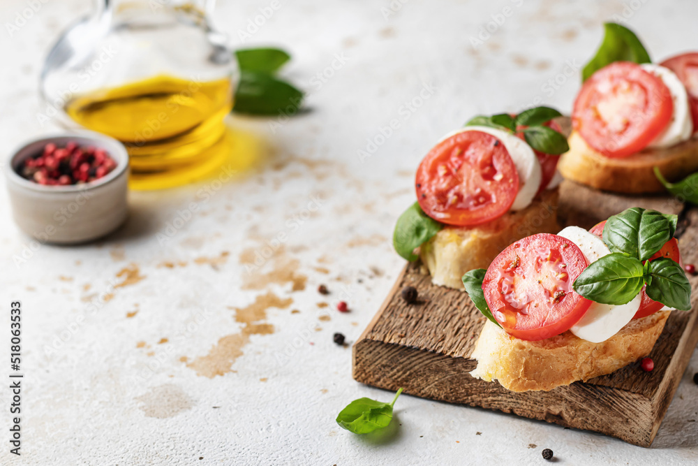 Bruschetta with mozzarella, tomatoes and basil on rustic wooden board with text space. Vegetarian food. Healthy eating