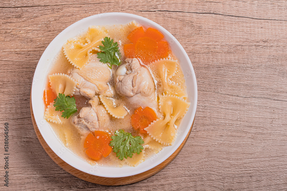 Macaroni soup with chicken thighs in clear broth with carrots.on an rustic old wood background. Macaroni soup with chicken thighs in clear broth with carrots.on an rustic old wood background.
