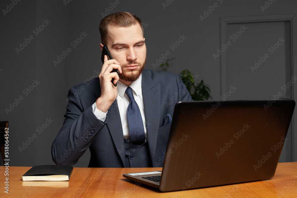 Businessman using laptop computer and phone indoor