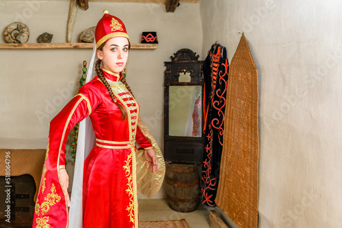 A girl in a bright red national dress dances in an ancient room of the adygea mountain peoples of the Caucasus Circassians