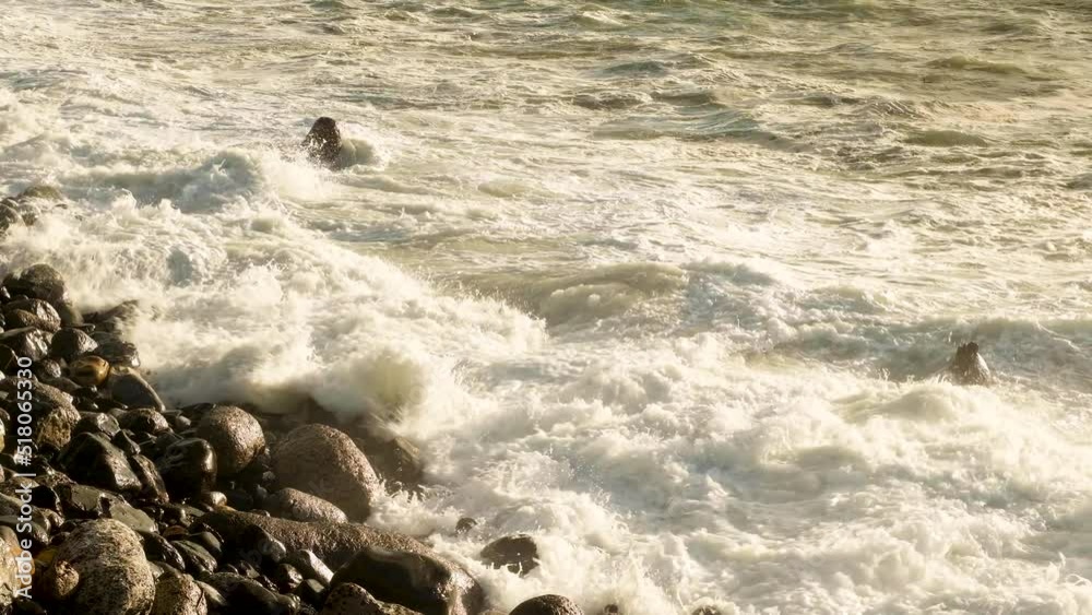 Waves at sunset hammering rock beach; close-up static shot Waves at sunset hammering rock beach; close-up static shot