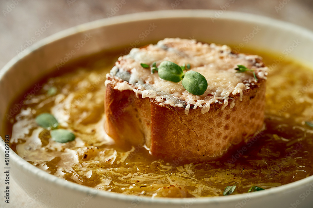 Onion soup with crouton in a bowl. A selective trick. Close-up. French cuisine. Onion soup with crouton in a bowl. A selective trick. Close-up. French cuisine.