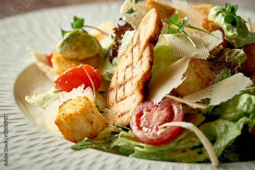 Caesar salad with grilled chicken in a plate. A selective trick. Close-up. Noise in post-production