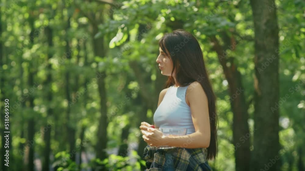 happy woman enjoying eating ripe strawberries while standing in the forest during family vacation. happy woman enjoying eating ripe strawberries while standing in the forest during family vacation.