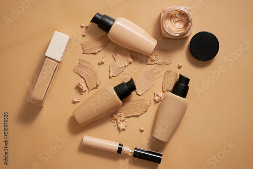 Bottles of makeup foundation and samples on beige background