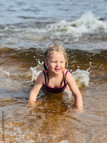 Little girl lying in sea in waves