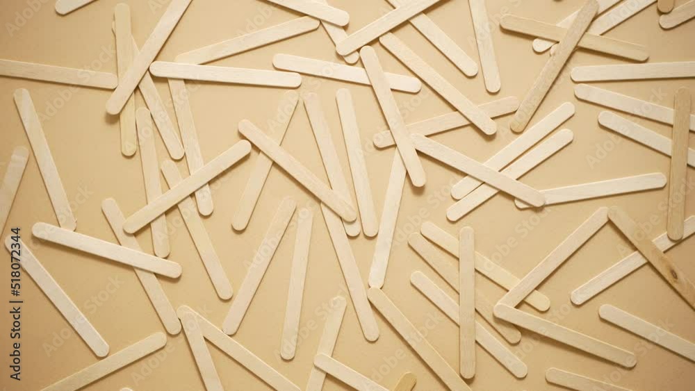 Wooden popsicle sticks, scattered on top of a beige background Wooden popsicle sticks, scattered on top of a beige background