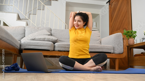 Attractive woman doing warming up stretching body on yoga mat before exercise at home