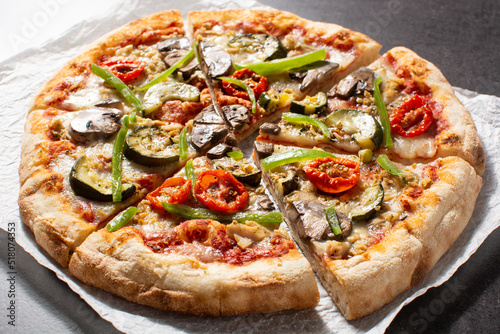 Vegetarian pizza with zucchini, tomato, peppers and mushrooms on black stone background
