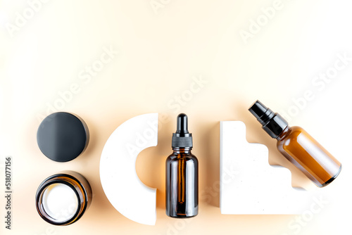 Set of amber glass cosmetic bottles on baige background. dropper bottle and cream jar package. Skincare beauty products packaging design fro daily routine