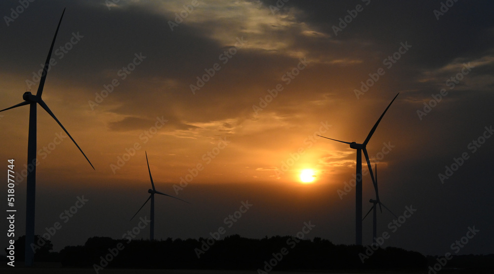 Obraz premium wind turbine at sunset, wind farm producing green clean renewable energy