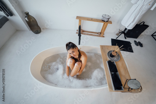 Valokuva Young woman hugs her legs while sitting in the bath