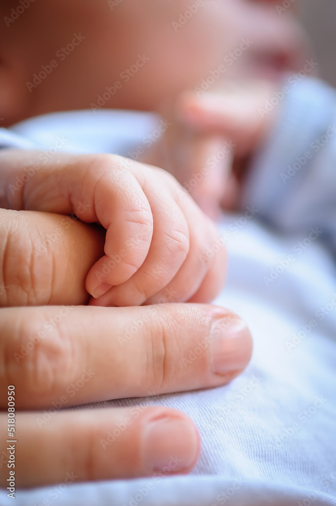 Close-up detail macro view of baby holding on to mom's finger with his little hand. Soft child skin. Love and family emotion Close-up detail macro view of baby holding on to mom's finger with his little hand. Soft child skin. Love and family emotion