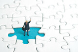 Miniature people toy figure photography. A businessman standing above missing piece of puzzle jigsaw while raise his hand