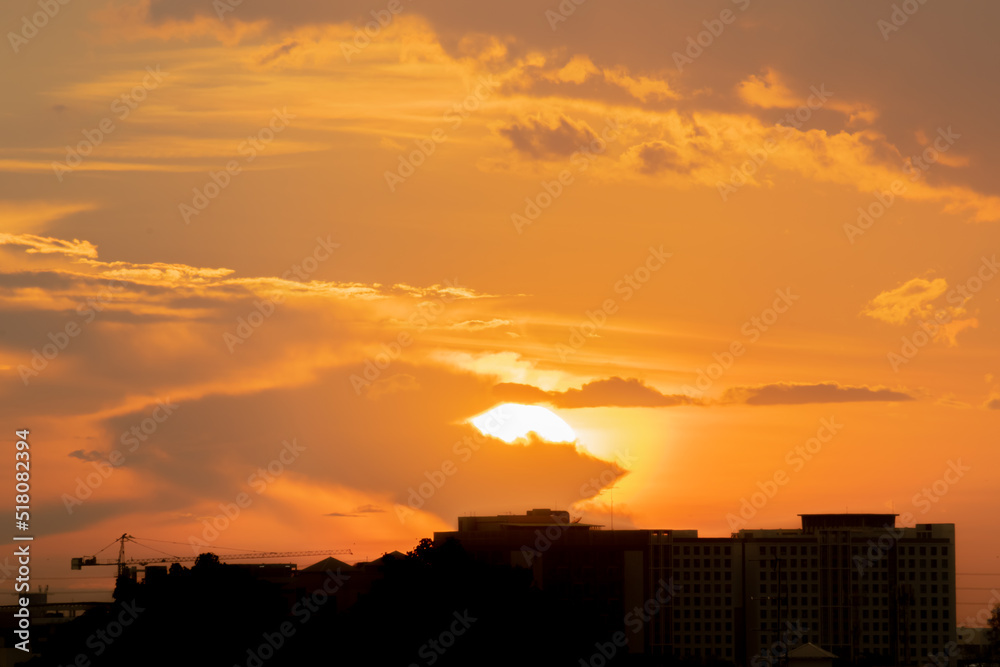 Gives a warm feeling, sunset behind the city building, silhouette city ​​tall buildings, building silhouette again beautiful sky background and freedom concept.