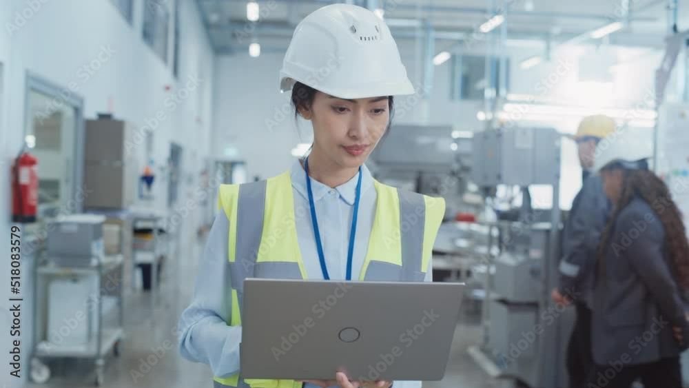 Portrait of a Happy and Smiling Asian Female Engineer in White Hard Hat Standing with Laptop Computer at Electronic Manufacturing Factory. Successful Heavy Industry Specialist Posing for Camera. Portrait of a Happy and Smiling Asian Female Engineer in White Hard Hat Standing with Laptop Computer at Electronic Manufacturing Factory. Successful Heavy Industry Specialist Posing for Camera.