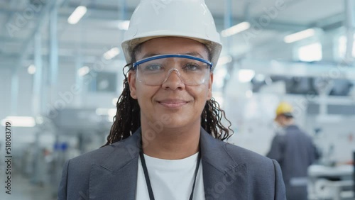 Close Up Portrait of a Successful, Happy and Smiling African Female Engineer in White Hard Hat Standing at Electronics Manufacturing Factory. Black Heavy Industry Specialist Posing for Camera. photo