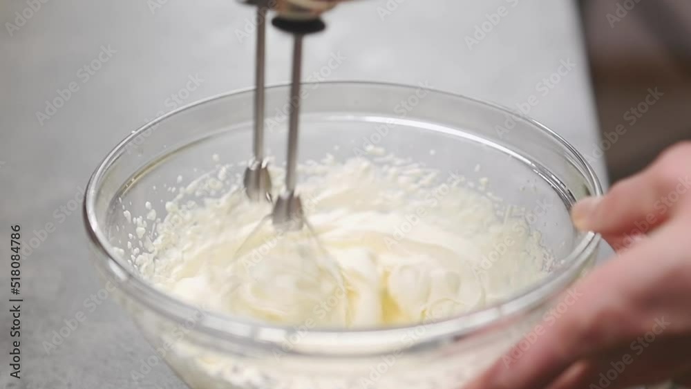 Whipping of cream in a glass bowl with mixer, slow motion. Whipping of cream in a glass bowl with mixer, slow motion.