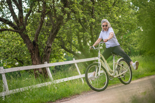 Fototapeta Naklejka Na Ścianę i Meble -  A woman in sportswear riding a bike in a park