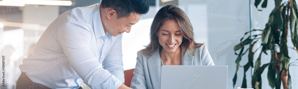 Confident asian office worker discussing work with mature female business woman. Blurred background Confident asian office worker discussing work with mature female business woman. Blurred background