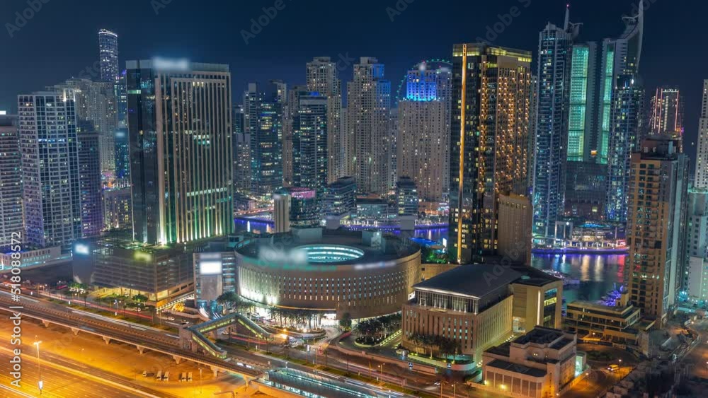 Dubai Marina skyscrapers with shopping mall and Sheikh Zayed road with metro railway aerial night timelapse. Traffic on a highway near modern towers from above, United Arab Emirates Dubai Marina skyscrapers with shopping mall and Sheikh Zayed road with metro railway aerial night timelapse. Traffic on a highway near modern towers from above, United Arab Emirates