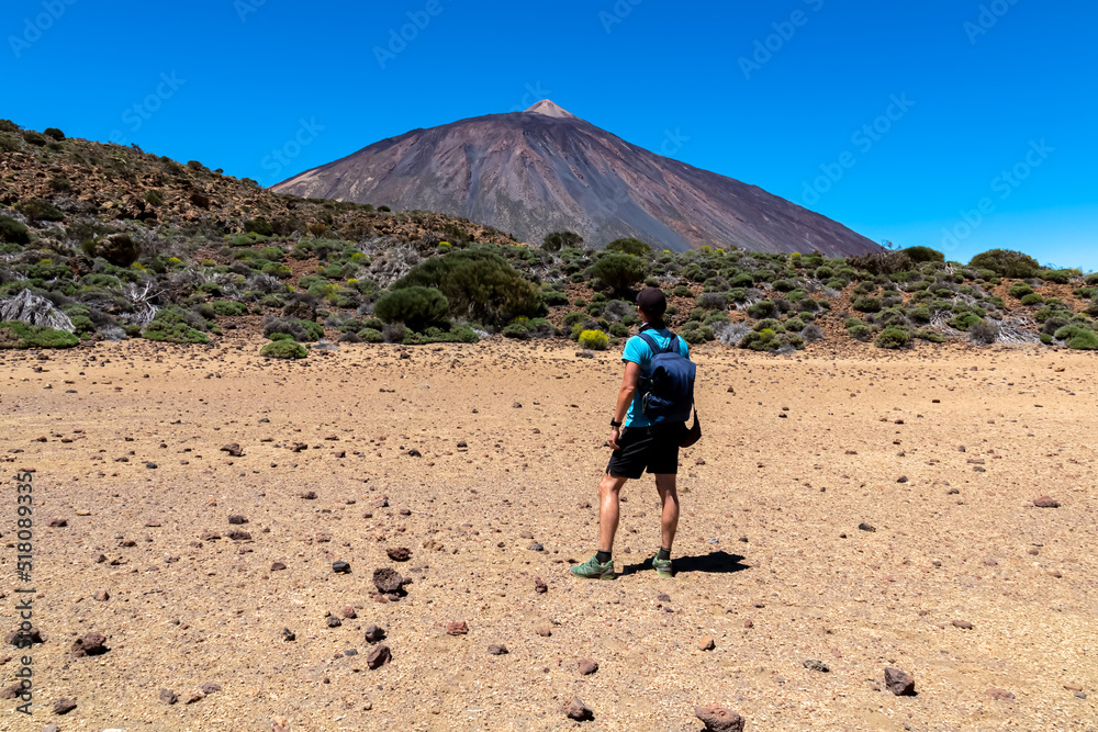 Active man on La Canada de los Guancheros dry desert plain with view on volcano Pico del Teide, Mount El Teide National Park, Tenerife, Canary Islands, Spain, Europe. Hiking to Riscos de la Fortaleza