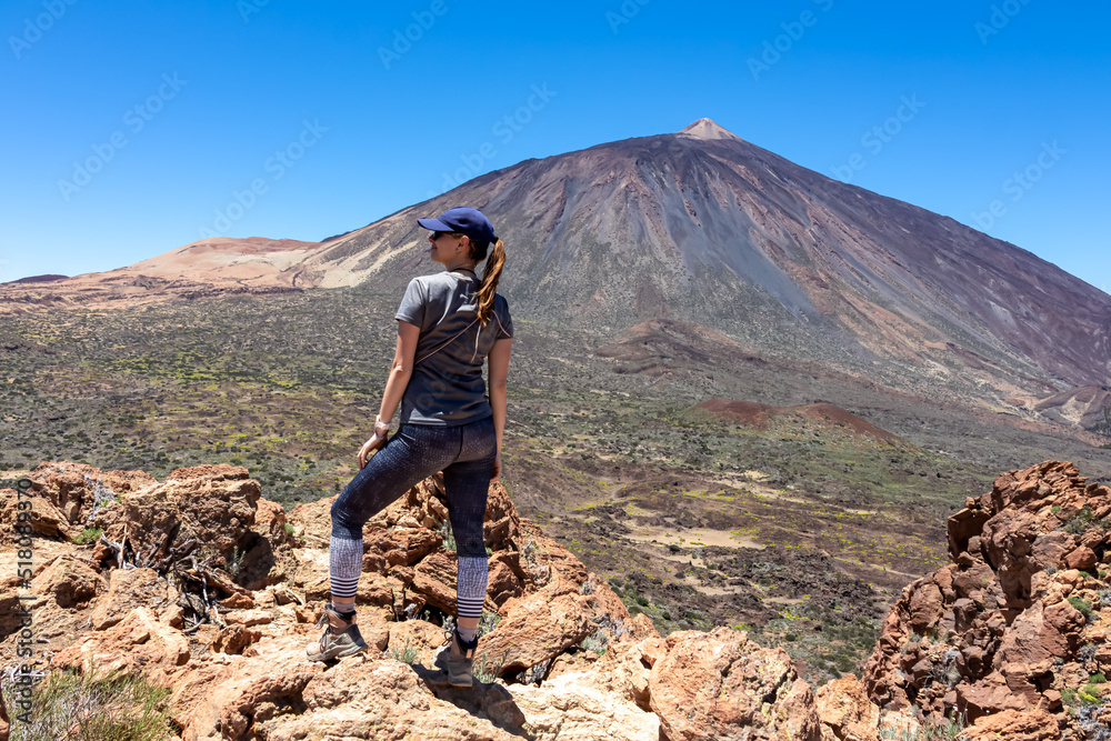 Woman on summit of Riscos de la Fortaleza with panoramic view on volcano Pico del Teide, Mount El Teide National Park, Tenerife, Canary Islands, Spain, Europe. Hike via La Canada de los Guancheros