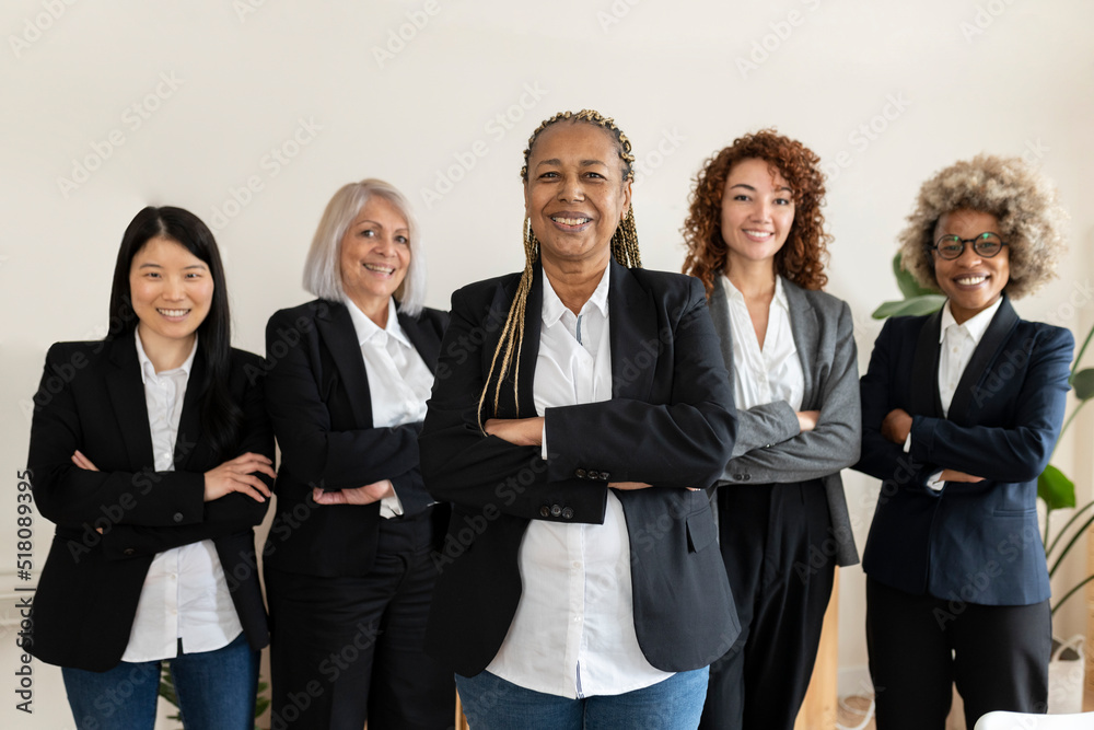 diverse women of different ages, multiracial, businesswomen in office, looking at camera with arms crossed, focus on african american woman