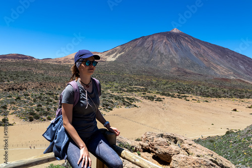 Woman on rock with view on La Canada de los Guancheros dry desert plain and volcano Pico del Teide, Mount Teide National Park, Tenerife, Canary Islands, Spain, Europe. Hiking to Riscos de la Fortaleza photo