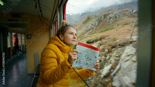 Happy and excited female traveler look out of train window. Young adult on trip of lifetime, student on vacation or interrail european trip. Exciting adventure on swiss train. Wandelust inspo