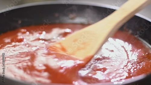 Cooking and stirring delicious tomato sauce in the frying pan.