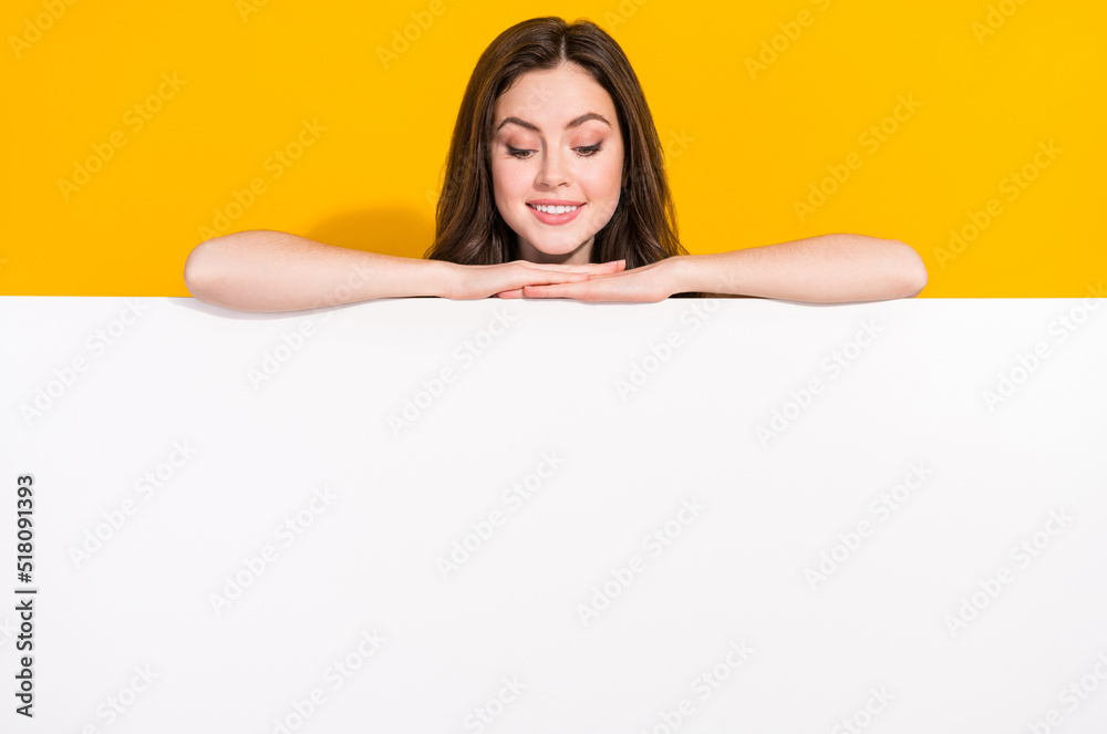 Photo of satisfied funky girl hide behind empty space blank look down isolated on yellow color background Photo of satisfied funky girl hide behind empty space blank look down isolated on yellow color background