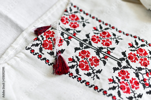 Fragment of Ukrainian national dress. Vyshyvanka - ethnic clothing with embroidery patterns. red and black threads. Close-up shot, copy space.