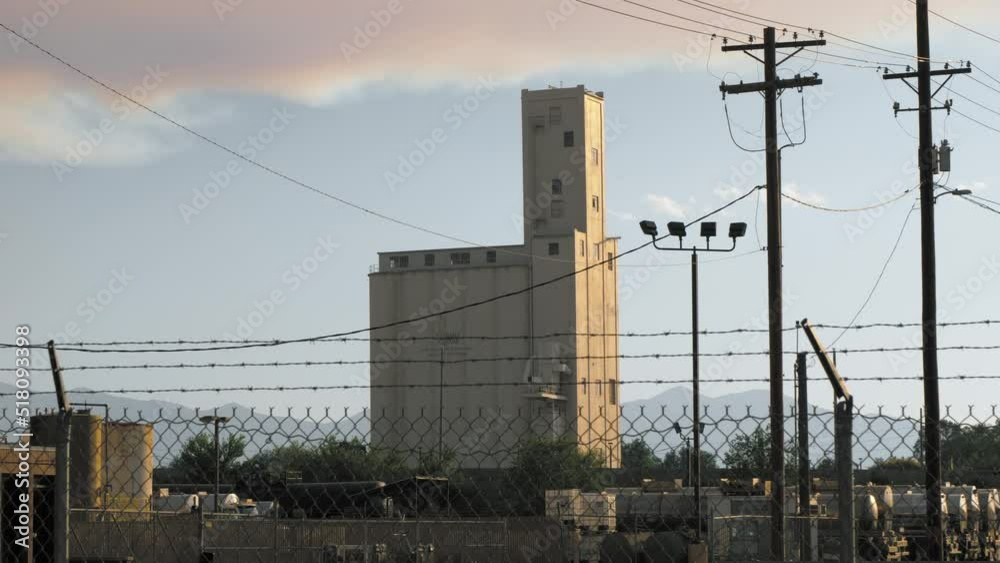 Grain silo in urban industrial setting with barbed wire fence and highway Grain silo in urban industrial setting with barbed wire fence and highway