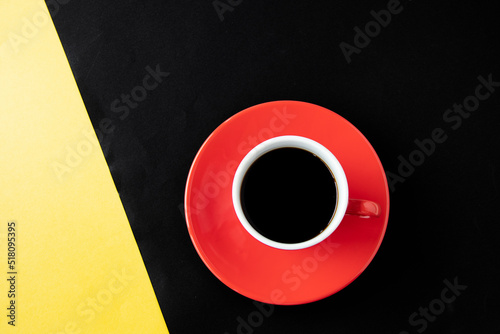 黄色と黒の紙の上の赤いコーヒーカップのコーヒー