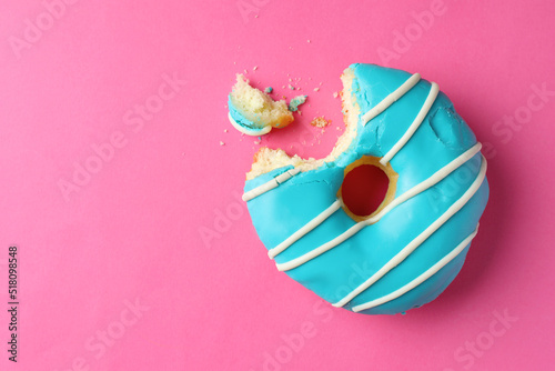 Fotografi Sweet bitten glazed donut on pink background, top view
