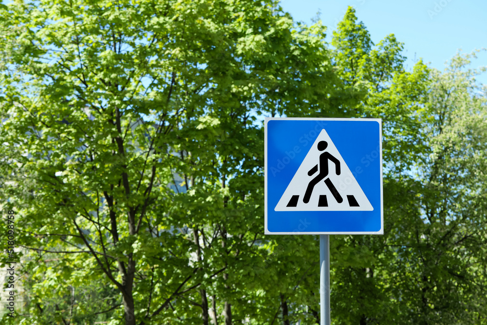 Post with Pedestrian Crossing traffic sign against trees on sunny day