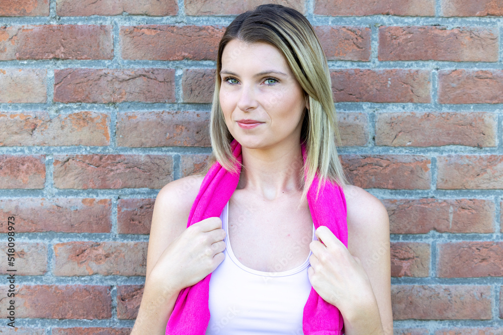 Portrait of a sporty sexy and vivacious young caucasian blonde sporty woman in pink sports clothing with a pink towel around neck resting after a workout. High quality photo Portrait of a sporty sexy and vivacious young caucasian blonde sporty woman in pink sports clothing with a pink towel around neck resting after a workout. High quality photo