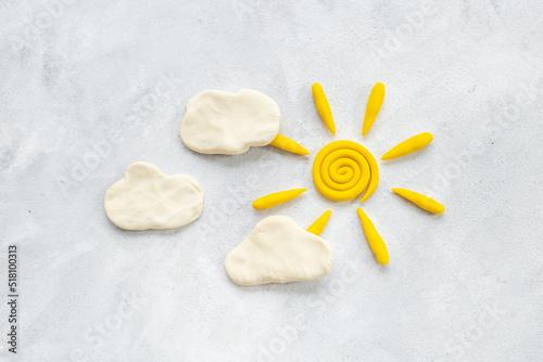 Weather forecast concept with plasticine sun and clouds, top view