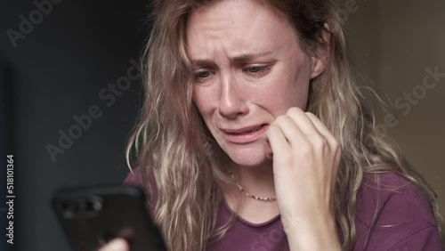 Sad woman looking at the smartphone and crying.