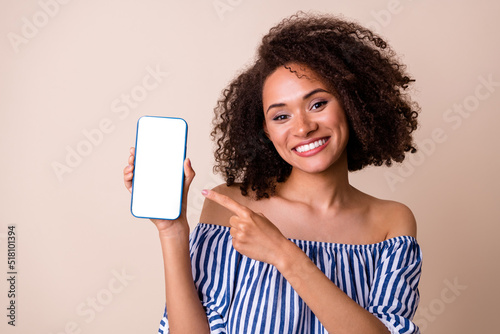 Portrait of gorgeous lady indicate finger hand hold telephone empty space screen isolated on beige color background