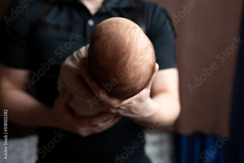 the head of a newborn in the palm of his father. small head of a newborn. child in the arms of a parent