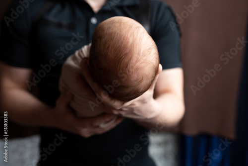 the head of a newborn in the palm of his father. small head of a newborn. child in the arms of a parent
