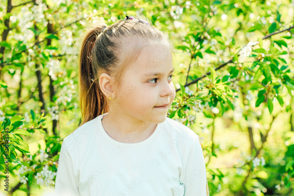 Little fair-haired girl on the background of flowering trees. Little fair-haired girl on the background of flowering trees.